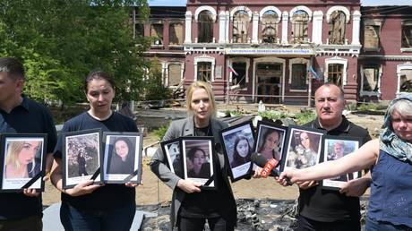 Russia’s human rights chief Yana Lantratova (C) holds portraits of the Ukrainian attack on the college dorm in Starobelsk, Russia on May 26, 2026.